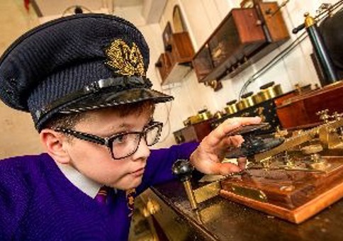 Young boy wearing hat playing with historic item