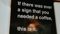 Large black sign, featuring the slogan "If ever there was a sign you needed a coffee, this is it." preview