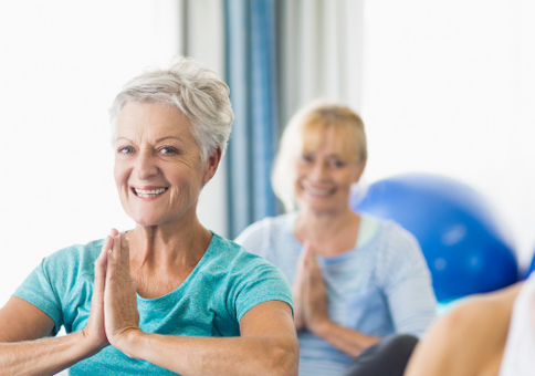 Smiling woman with hands in prayer in yoga class
