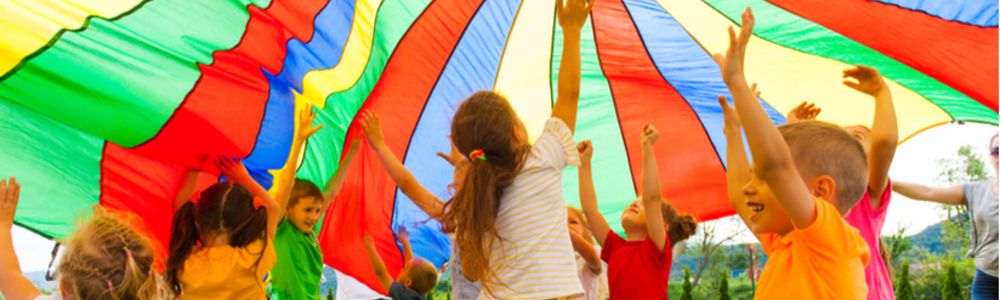 Group of children playing with large multu-coloured parachute