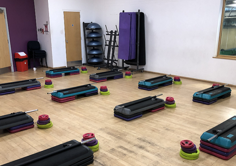Exercise studio with step, bar and weights laid out ready for a class