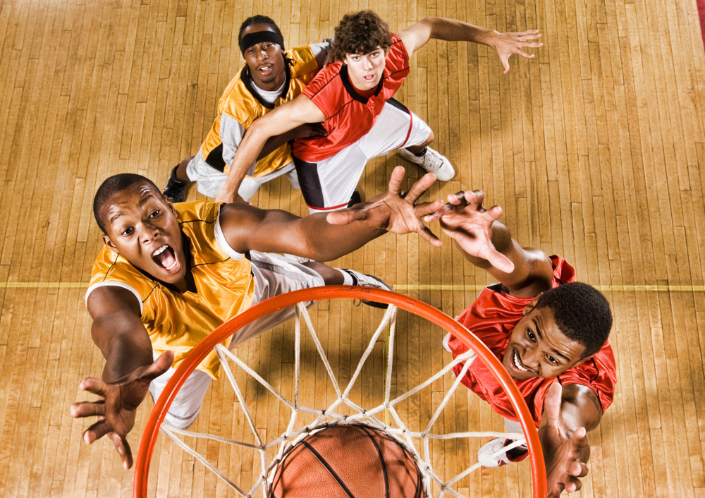 Four men reaching up towards basketball hoop