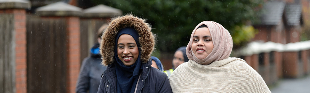 Two ladies in headscarves on a walk in a suburban area