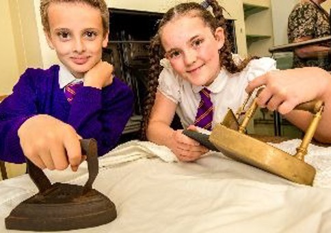 Children holding Victorian historic items and looking at camera