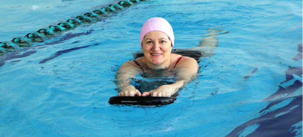 Woman in pink swimming hat in pool using a float