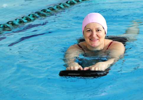 Woman in pink swimming hat in pool using a float