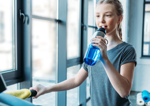 Younger teen girl sipping water on treadmill