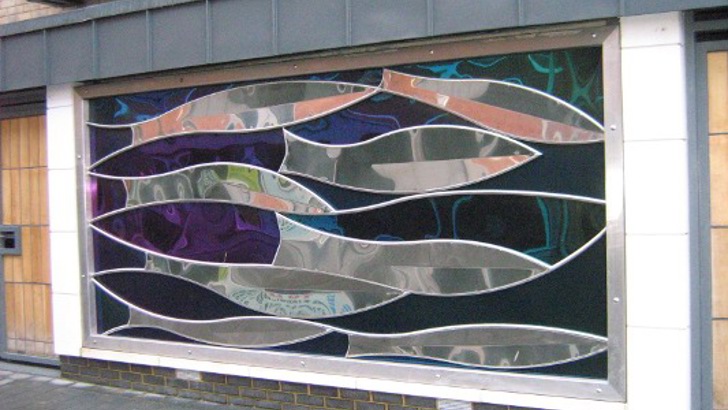 Steel sculpture of fish on the side of a building
