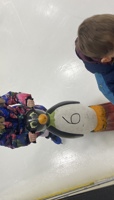 Young girl ice skating holding onto a plastic penguin aid for balance preview