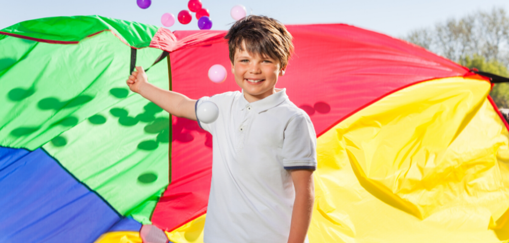 Boy playing with multi-coloured parachute and balls