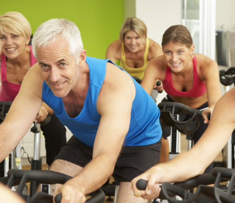 A group of adults participate in a cycling exercise class