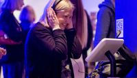 A woman wearing headphones and looking at a tablet at the Forecast22 launch.  preview