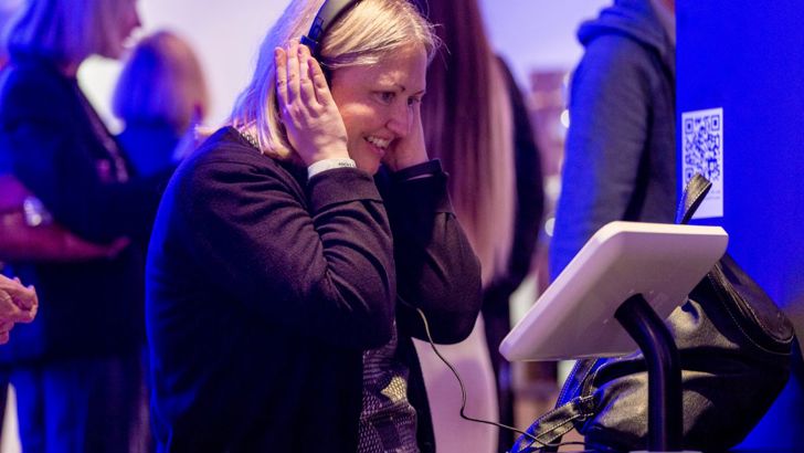 A woman wearing headphones and looking at a tablet at the Forecast22 launch. 