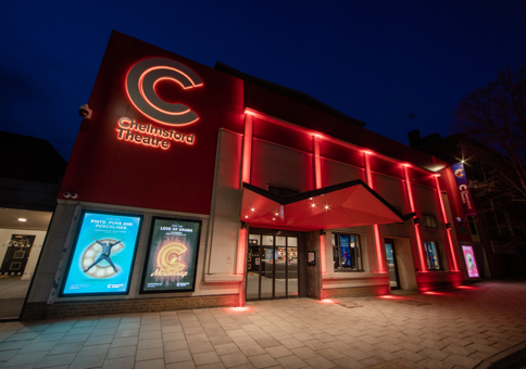 Chelmsford Theatre at night, with frontage lit up in red