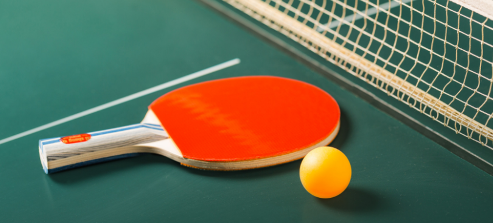 Red bat and orange ball on a table tennis table