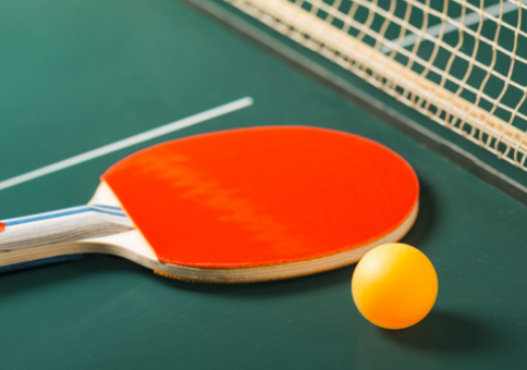 Red bat and orange ball on a table tennis table