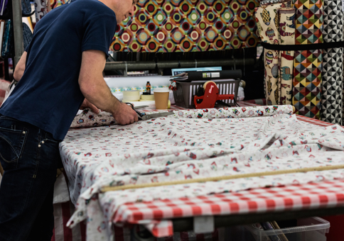 Man cutting fabric on market stall