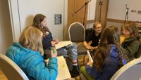 A group of kids at Radio Club sit in a circle working on their scripts.  preview